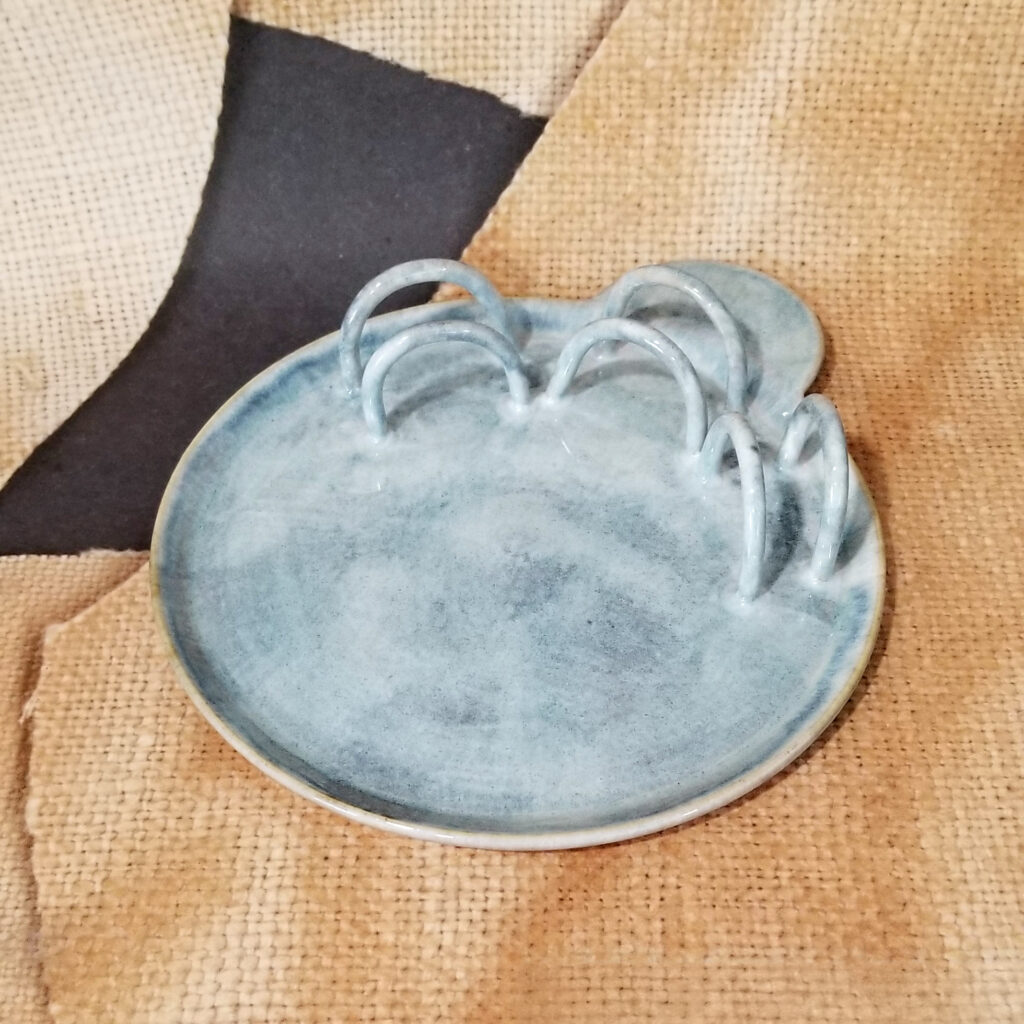 7.5 inch plate with little loops to hold cookies and a round handle. The plate is painted light blue with a mild white wash.